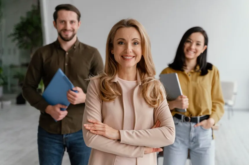 Three smiling professionals stand together in modern office as business directory lists your business